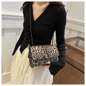 Detalle de bolso bandolera de leopardo con cadena negra y cierre plateado