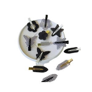 Set of 11 polka dot hair clips in flower and star shapes on a white ceramic plate