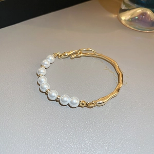 Close-up of gold-plated bracelet with freshwater pearls and wavy metal rod details