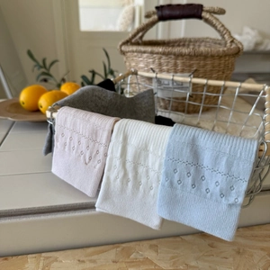 Close-up of pastel cotton socks with delicate hollow flower patterns on a white basket