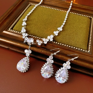 Dettaglio macro del set collana e orecchini con zircone a goccia su velluto retrò