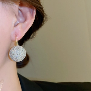 Macro view of gold-plated ball drop earrings with micro-paved sparkling rhinestones