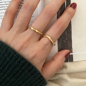 Close-up of stacked minimalist golden bamboo and wave rings on finger for women
