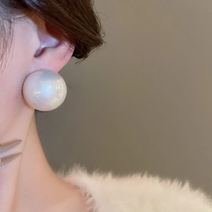 Gros plan d'une élégante boucle d'oreille perle irisée sur modèle en fourrure blanche