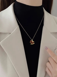 Close-up of 18K gold plated horse pendant necklace with red enamel and white zircon stones