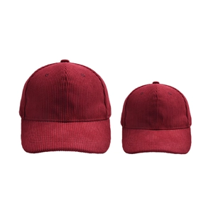 Detail of adult and child size burgundy corduroy baseball caps showing soft ribbed texture