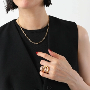 Close-up of a gold O-chain necklace and two-tone layered ring on a model