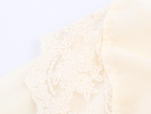 Close-up of beige French style dress featuring delicate lace embroidery and fabric seams
