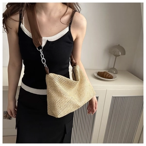 Detailed view of woven tote with brown leather strap and silver chain on model