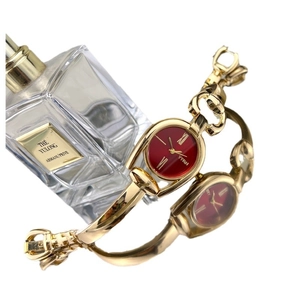 Vintage gold bangle watch for women with a deep red dial and elegant Roman numerals