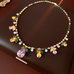 Detailed close-up of colorful pear and leaf-shaped gemstones on a gold luxury necklace