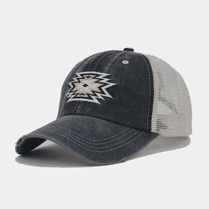 Detailed close-up of distressed brim and geometric embroidery on mesh ponytail cap
