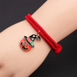 Close-up of a red woven Halloween bracelet featuring an alloy pumpkin wizard hat charm