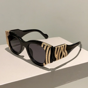 Detail of black thick-frame sunglasses featuring elegant golden textured metal temples