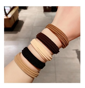 Detail of high-elastic knit hair ties in five earth tones worn on a model wrist