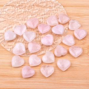 Natural rose quartz heart stones 25mm scattered on a wooden tray for energy healing