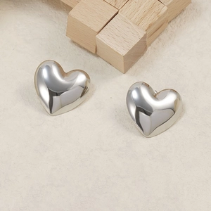 Macro detail of polished silver heart stud earrings in 18K plated stainless steel