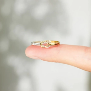 Macro detail of bicolor S925 silver knot ring with polished gold and silver woven texture