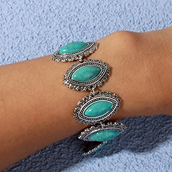 Close-up of vintage bohemian turquoise heart bracelet on a model's wrist with silver metal detail