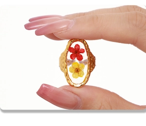 Detailed close-up of a gold ring featuring red and yellow dried flowers in clear resin