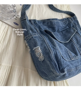 Détail d'un sac cabas en denim bleu avec bords effilochés et une poche frontale à rabat