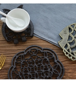 Close-up of rustic cast iron trivets in owl and fish shapes on a wooden tabletop
