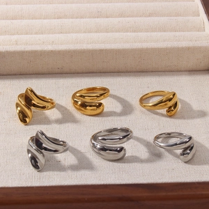 Macro view of polished 18K gold and silver teardrop rings on a beige linen jewelry tray