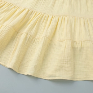Detailed close-up of light yellow tiered skirt featuring pleated cotton linen texture