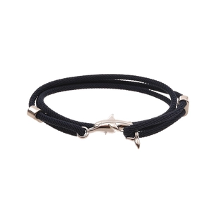 Detail of black woven cord bracelet featuring a polished silver shark anchor clasp