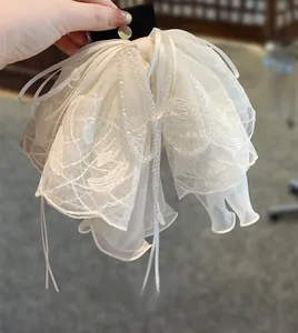Détail d'une grande pince à cheveux en dentelle beige avec des perles délicates