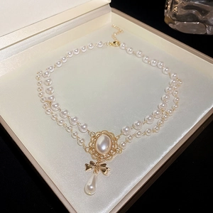 Double-layered pearl necklace featuring a golden oval gem and bow pendant in a gift box