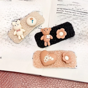 Cute plush cartoon hair clips with bear and rabbit designs on a vintage book background