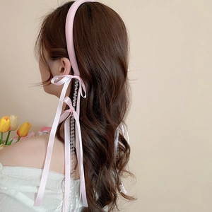 Detail of pink satin headband with elegant ribbon streamers and crystal bead tassels