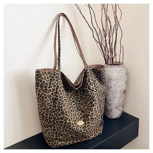 Detail of leopard print tote bag with golden handmade metal plate on a shelf