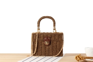 Macro shot of dark brown woven box bag with metal chain strap and gold twist lock
