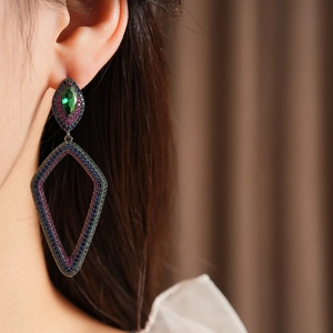 Close-up of vintage geometric earrings with multicolor gemstones worn by a model