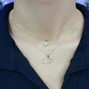Close-up of double-layered gold necklace featuring Arabic letter pendants with zircon inlay