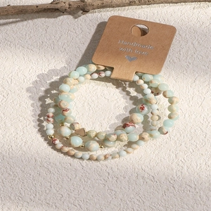 Detail of handmade stone beaded bracelets with heart charm on kraft display card