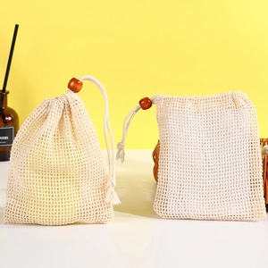 Natural jute soap foaming net bags with wooden bead drawstring on a modern desk