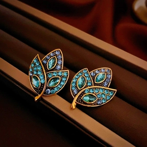Vintage leaf earrings with blue crystals and gold finish on brown velvet background