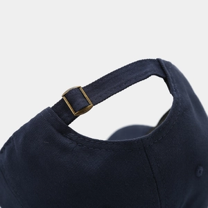 Detail of adjustable metal buckle and navy cotton strap on baseball cap back