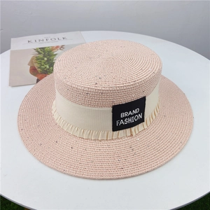 Detail eines rosa Strohhutes mit Pailletten, Rüschenband und Mode-Label auf flacher Oberseite