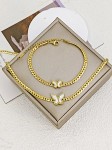 Detail view of gold butterfly pendant set with white shell inlay on cuban chain link