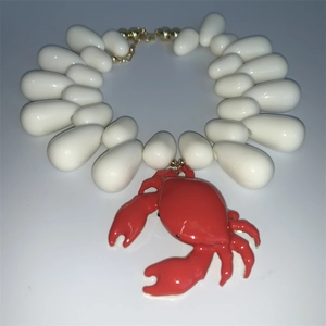 Detailed view of ocean-style white teardrop bead necklace with a red crab pendant