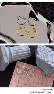 Detail view of gold and silver hoop earrings on artistic minimalist stone props