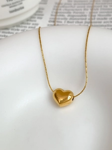 Macro view of gold heart pendant necklace on white ceramic with book backdrop