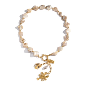 Detail of beaded necklace with gold starfish, shell, fish, and lobster pendants on white background