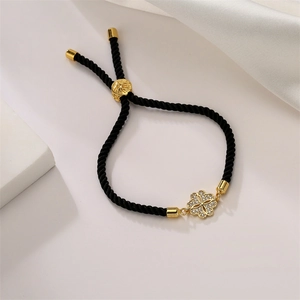 Détail du bracelet tissé noir ajustable avec trèfle en or et zircons incrustés