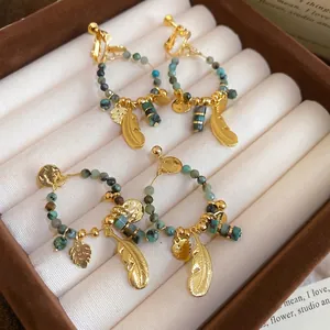 Bohemian gold plated feather earrings with green turquoise beads in a jewelry box