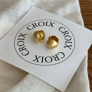 Detailed close-up of matte brushed gold spherical earrings on a branded display card